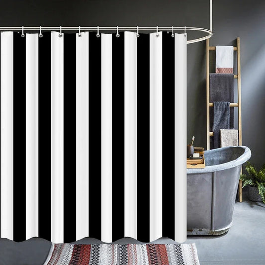 Rideau de douche à rayures noires et blanches suspendu sur une tringle arrondie, installé devant une baignoire en métal style industriel. Salle de bain élégante avec échelle porte-serviettes et tapis décoratif