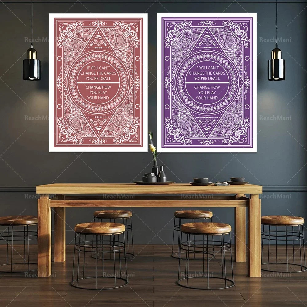 Deux grandes affiches murales décoratives encadrées, dotées de motifs ornementés et de textes inspirants, sont suspendues sur un mur sombre, tandis qu'une table en bois rustique avec des tabourets se trouve en dessous, créant une ambiance contemporaine et élégante.