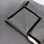 Un sac élégant noir et blanc orné de motifs géométriques, avec des poignées noires, posé sur une surface grise.