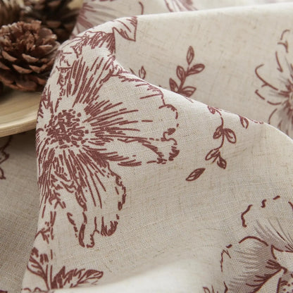 Gros plan du tissu à fleurs bordeaux sur fond beige, mettant en valeur la texture naturelle du rideau.