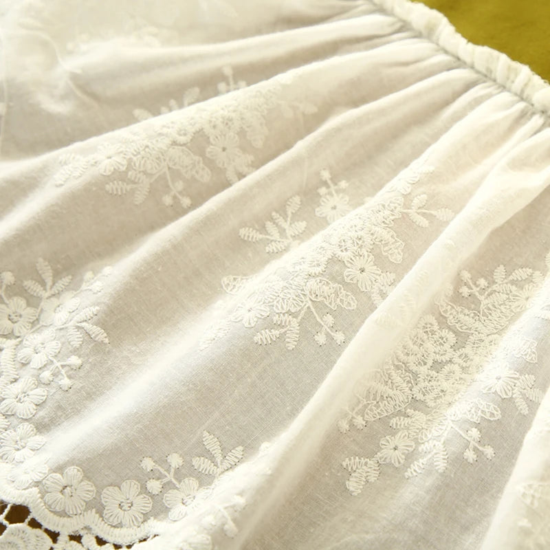 Un tissu blanc crème aux motifs fleuris délicats et élégants, suggérant une texture douce et une atmosphère raffinée.