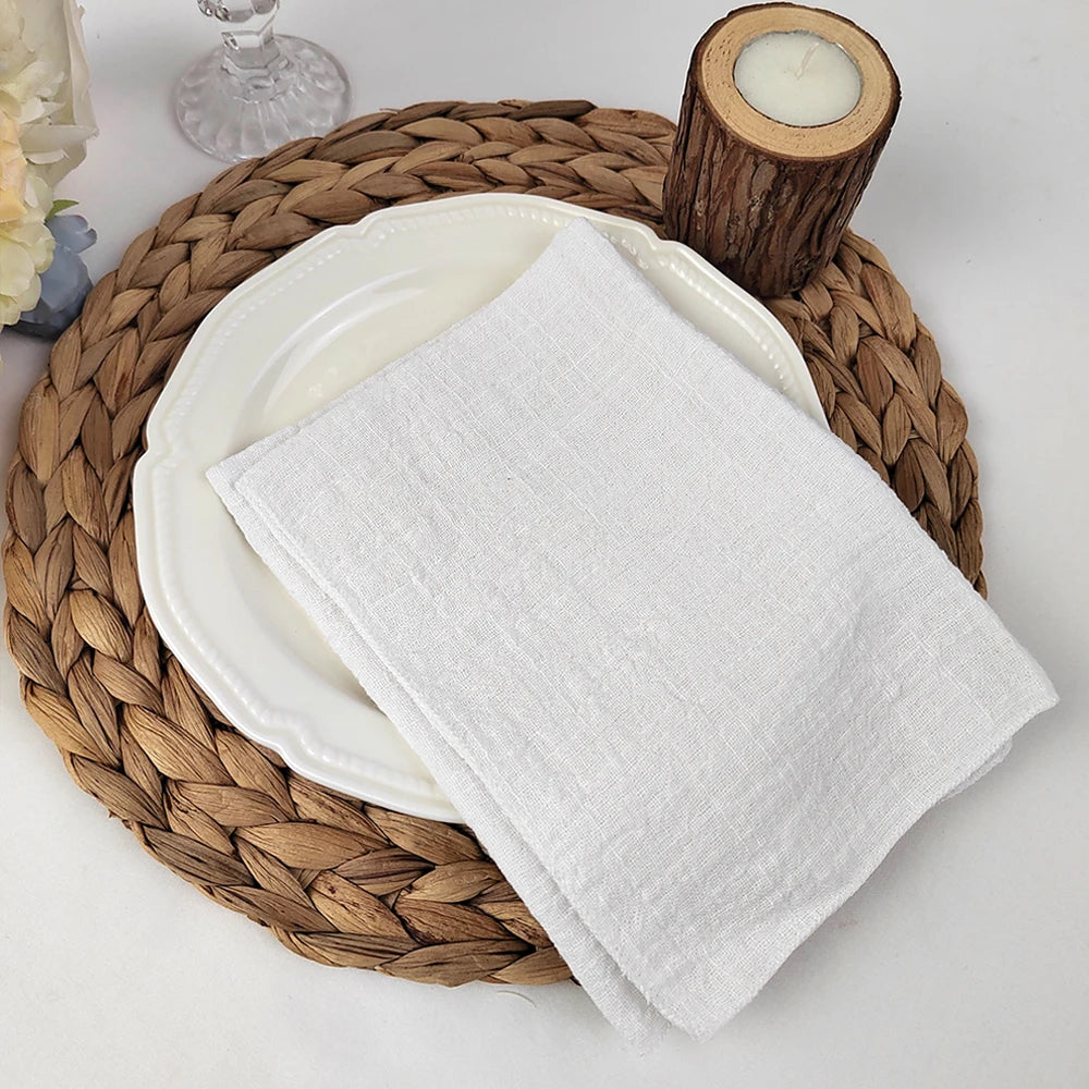 Sur une jolie natte en osier, une assiette blanche et une serviette en lin gris composent un arrangement élégant et minimaliste.