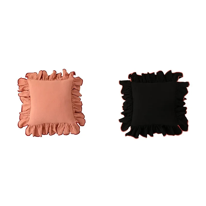 Ensemble de deux coussins carrés en tissu rose saumon et noir avec bords ornés de volants, offrant un élément de design décoratif élégant pour un intérieur.