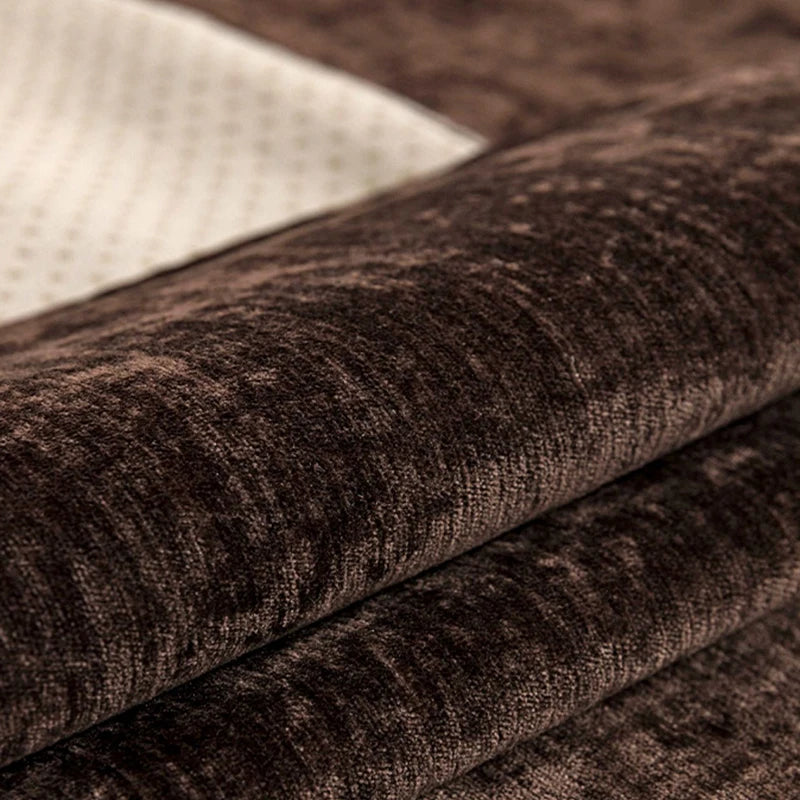 Cette image montre un gros plan d'un textile sombre et texturé, avec des plis et des ombres qui créent un effet de profondeur et de richesse visuelle.