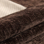 Cette image montre un gros plan d'un textile sombre et texturé, avec des plis et des ombres qui créent un effet de profondeur et de richesse visuelle.