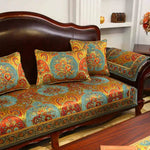 Canapé en bois foncé orné de coussins et de motifs colorés traditionnels, créant un décor élégant et riche en détails.