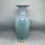 Vase en céramique de couleur vert clair avec des accents violets.