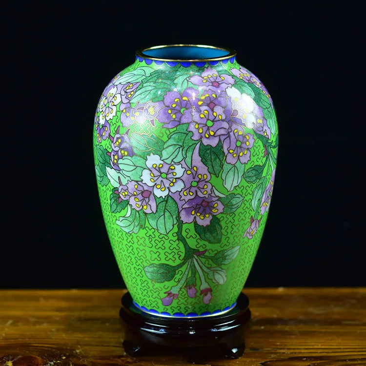 Un magnifique vase en porcelaine émaillé vert, orné de bouquets de fleurs violettes et de feuilles détaillées.