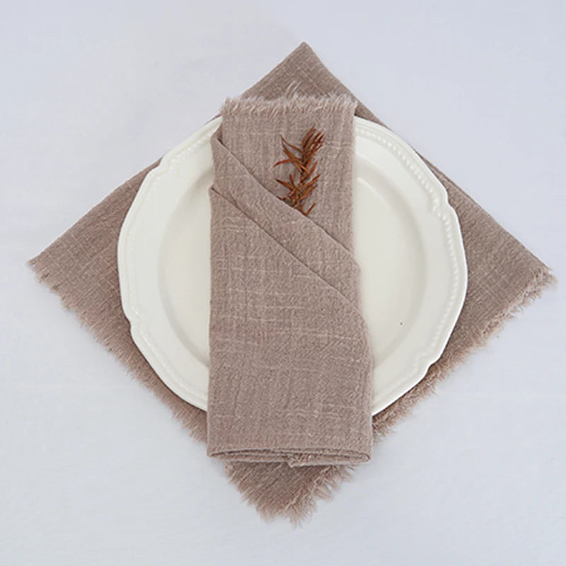 Une serviette de table beige ornée d'une décoration végétale rouge posée sur une assiette blanche.