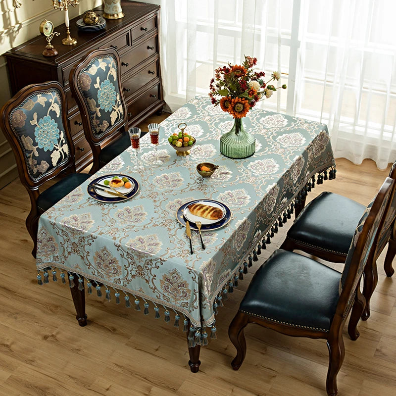 Une salle à manger élégante avec une table couverte d'une nappe fleurie, un bouquet de tournesols et des assiettes de pâtisseries, le tout dans un décor vintage et chaleureux.