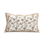 Un coussin décoratif avec un motif floral nuancé de beige sur un fond crème.