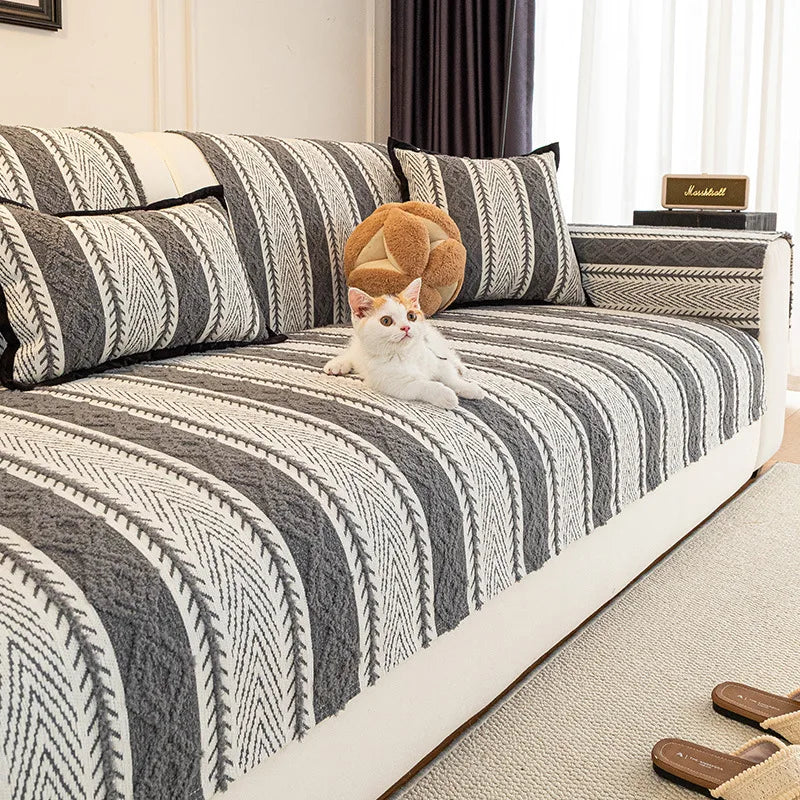 L'image montre un chat blanc allongé sur un canapé rayé en noir et blanc, avec des coussins aux motifs géométriques. Une enceinte Marshall est visible sur un meuble à côté.