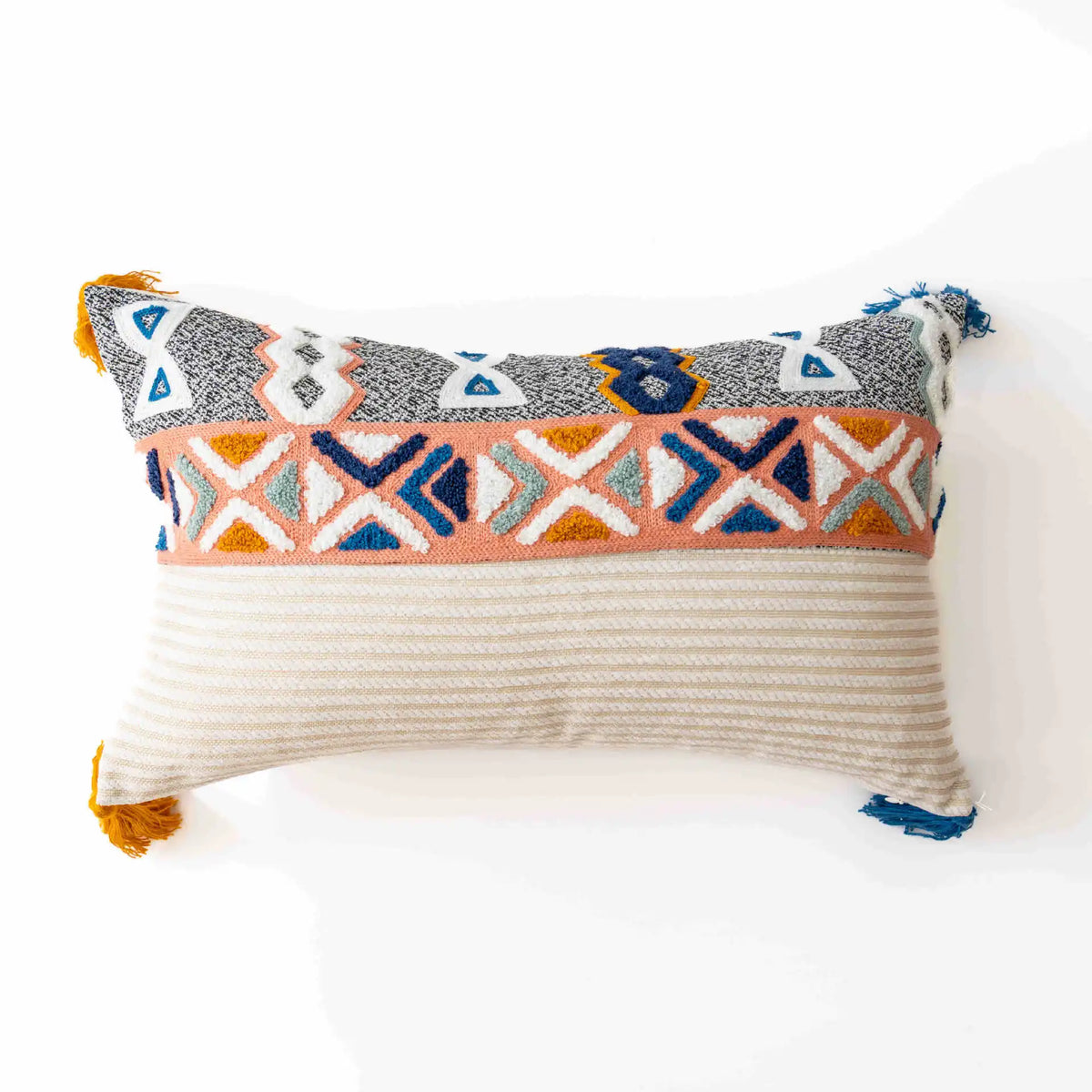 Coussin décoratif aux motifs géométriques multicolores sur fond blanc avec des franges.