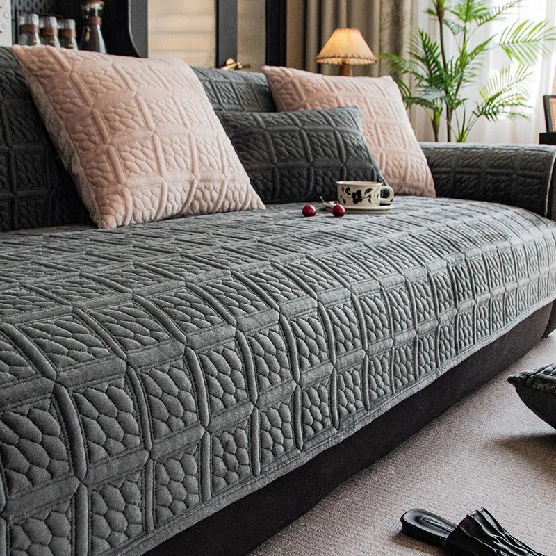 Cette image montre un canapé gris confortable avec des coussins assortis, disposé dans un salon élégant avec une plante verte en arrière-plan.