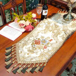 Une table élégante avec un chemin de table orné de broderies florales, une bouteille de vin et un bouquet de fleurs fraîches, créant une atmosphère chaleureuse et sophistiquée.