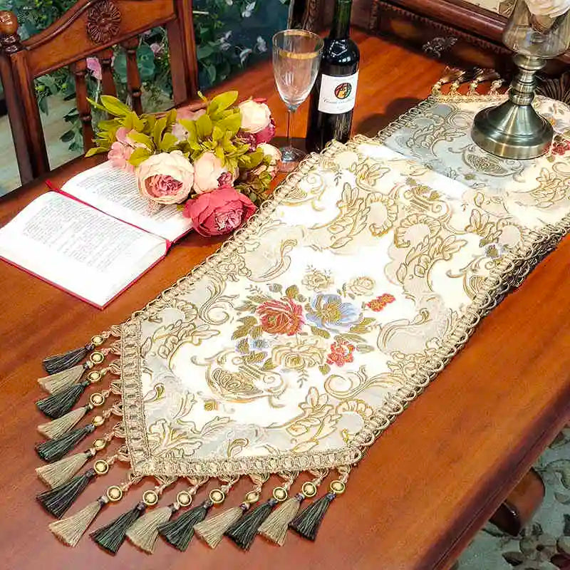 Une table élégante avec un chemin de table orné de broderies florales, une bouteille de vin et un bouquet de fleurs fraîches, créant une atmosphère chaleureuse et sophistiquée.