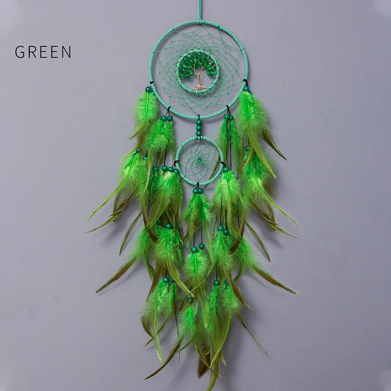 Un capteur de rêves décoratif vert orné de plumes et d'un arbre de vie au centre.