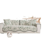 Canapé élégant avec des motifs de fleurs vertes et blanches, créant une atmosphère chaleureuse et confortable dans un intérieur moderne.