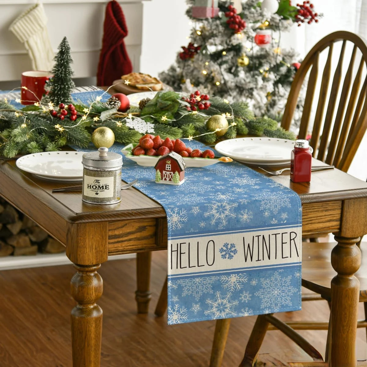 Une table de fête décorée pour l'hiver, avec des assiettes, des fruits rouges, une guirlande de Noël et un message de bienvenue à l'hiver.