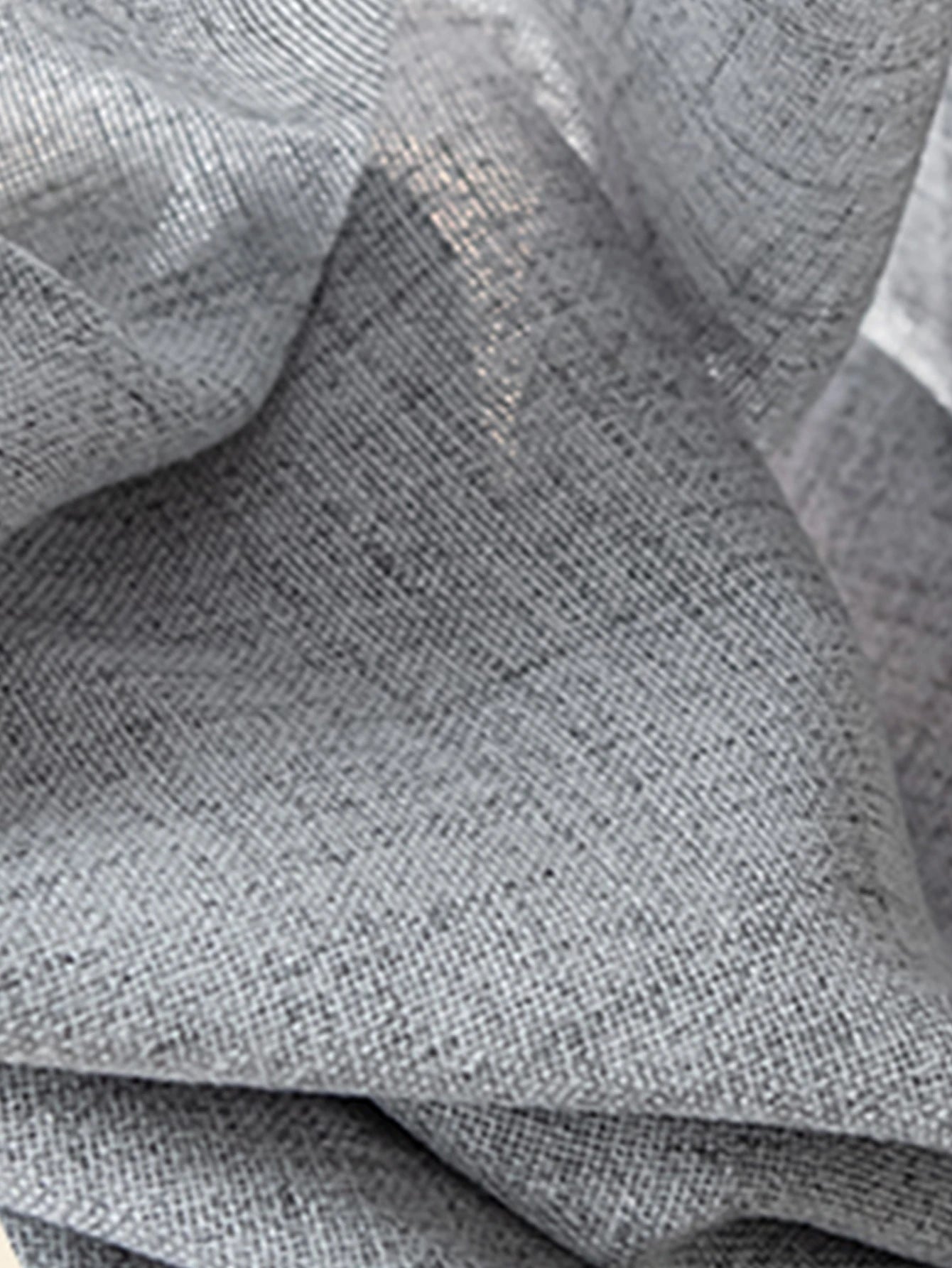 Détail du tissu du voilage gris clair tamisant mettant en valeur sa texture naturelle.