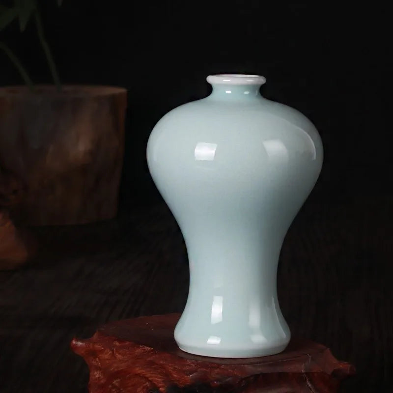 Un vase en céramique bleu clair posé sur un fond sombre.