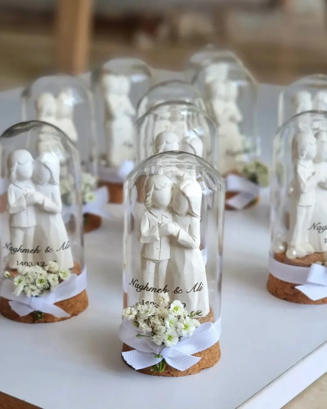 cloches verre transparent liège personnages sculptés fleurs artificielles couples blanc rose vert