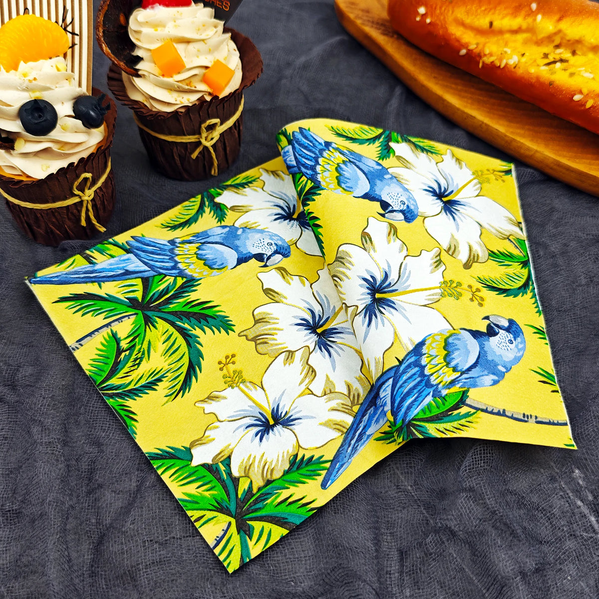 serviettes table papier motif tropical perroquets fleurs palmiers jaune bleu vert hibiscus pliées dépliées