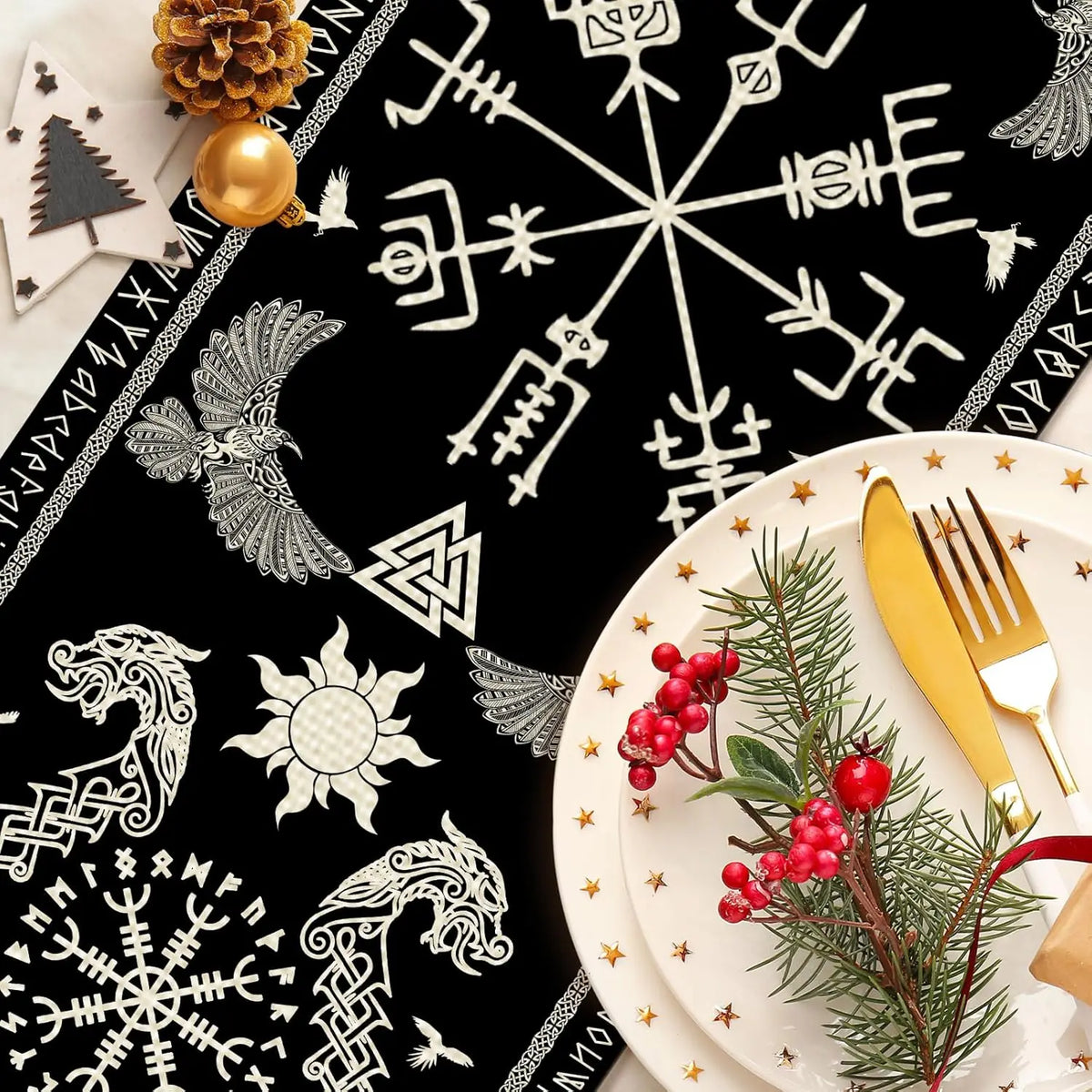 Cette image montre une belle assiette de Noël décorée avec des brindilles de sapin, des baies rouges et des couverts dorés posés sur un fond noir orné de symboles et motifs nordiques.