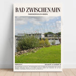 Photographie d'un quai paisible au bord d'un plan d'eau, entouré de végétation verdoyante et de bâtiments caractéristiques de Bad Zwischenahn, une ville allemande connue pour ses thermes et ses aménagements paysagers.