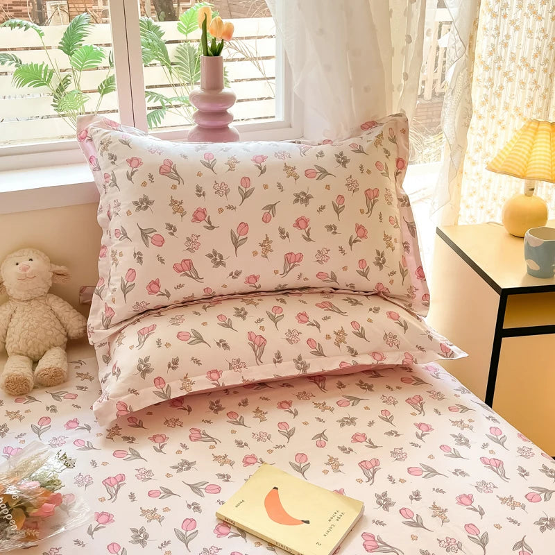 Cette chambre confortable présente un ensemble de literie orné d'un motif floral délicat et coloré, créant une ambiance chaleureuse et apaisante. Une lampe jaune et un petit animal en peluche ajoutent des touches de décoration agréables.