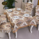 Cette image représente une belle nappe et ses accessoires de table, avec des fleurs et un motif décoratif délicat, conçus pour une salle à manger élégante.