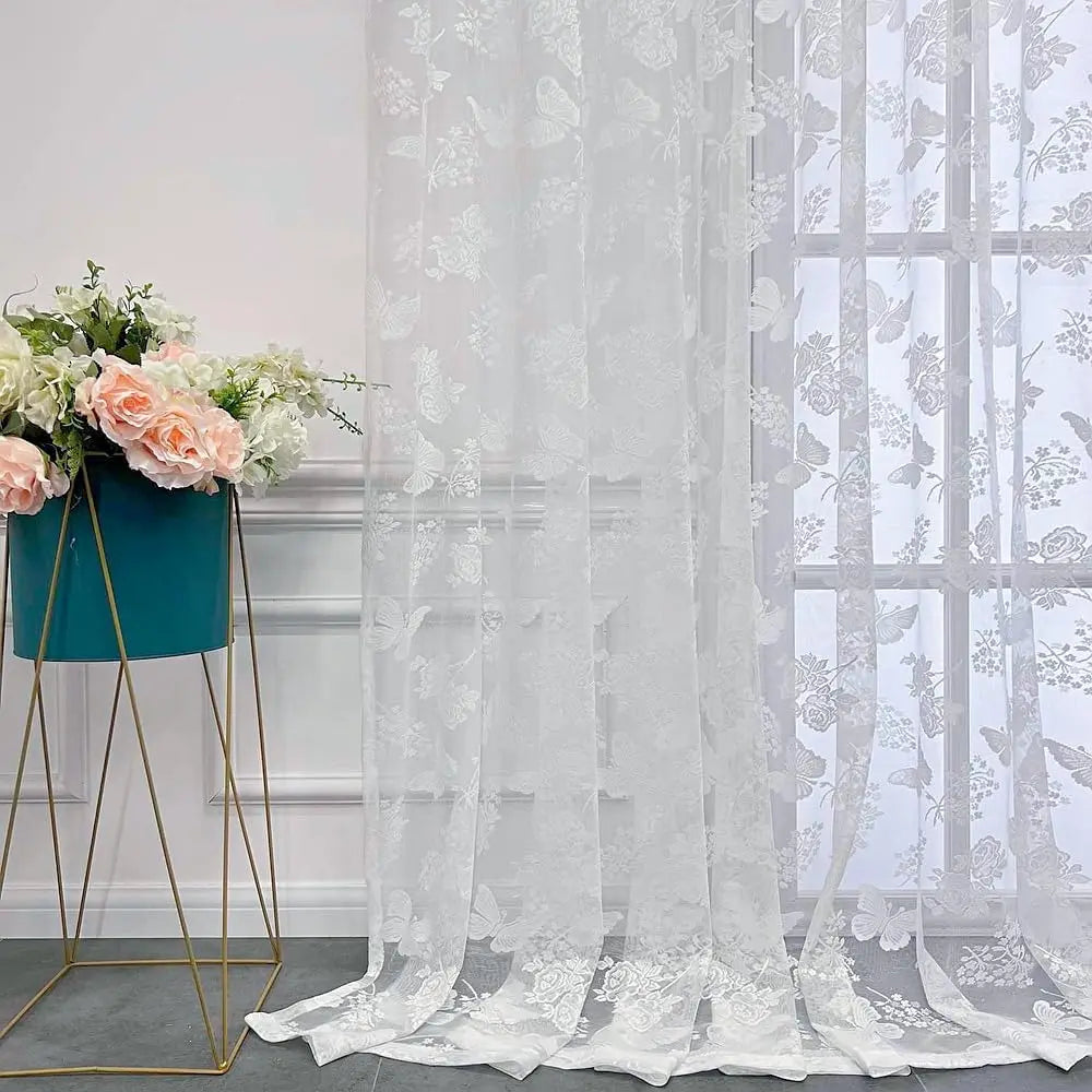 Voilage papillon blanc devant une fenêtre avec une table en bois et une horloge rétro posée dessus.