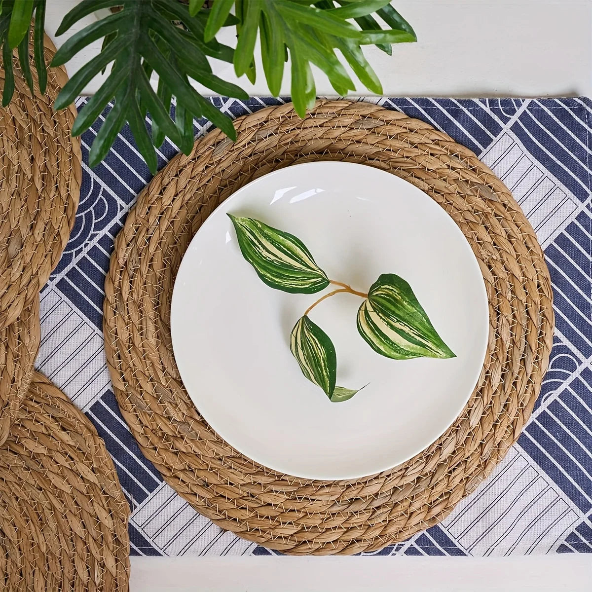 assiettes rustiques tissées spirales naturelles serviette blanche guirlande feuilles conques dorées decoration cuisine festive
