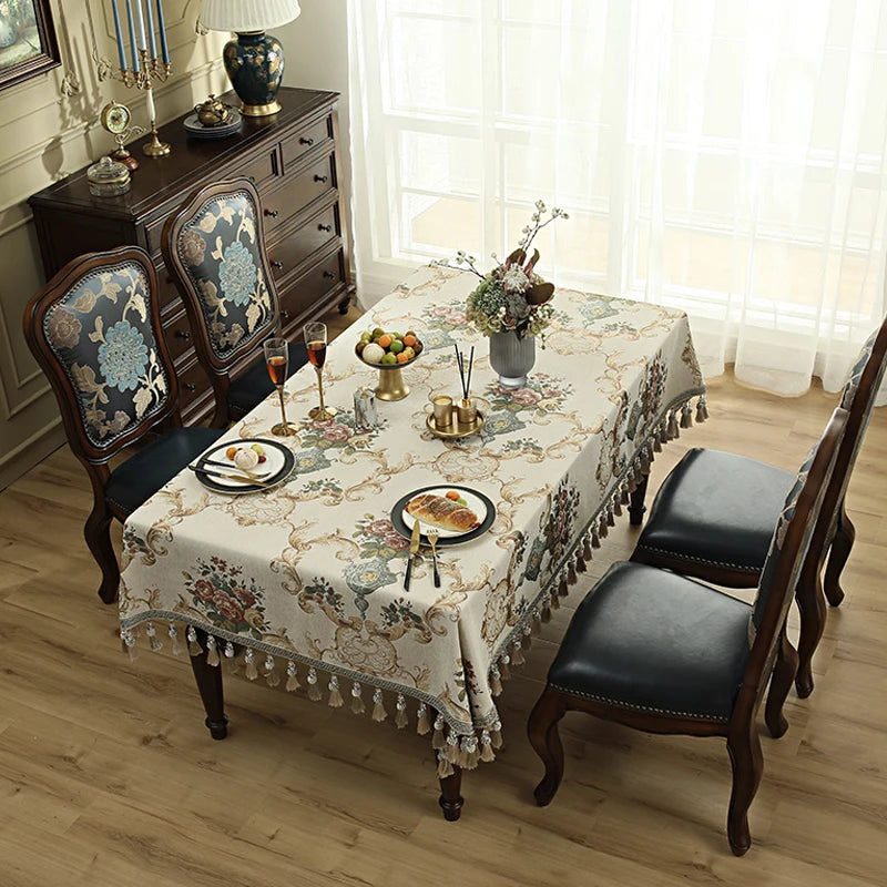 Une table de salle à manger élégante avec des motifs floraux sur la nappe et des accessoires de décoration vintage sur la surface.