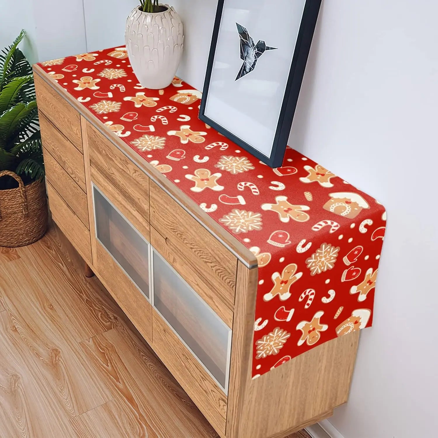 Meuble en bois avec un chemin de table décoré de motifs festifs rouges et dorés.