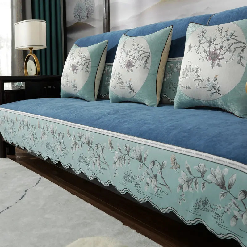 Canapé bleu et blanc décoré avec des motifs floraux et paysagers, avec des coussins assortis, dans un élégant décor d'intérieur.