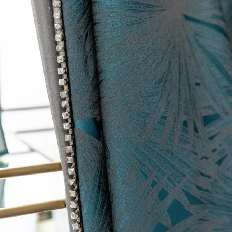 Chaise élégante avec des détails décoratifs en métal argenté, présentant un motif géométrique bleu. Le design raffiné et les accents luxueux en font un choix idéal pour sublimer l'intérieur de votre maison.