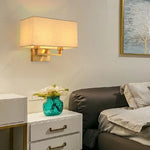 Applique murale LED double tête éclairant un coin salon avec abat-jour gris