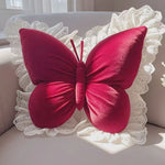 Ce coussin décoratif en forme de papillon rouge vif orné de dentelle blanche crée une impression chaleureuse et élégante sur ce meuble blanc.
