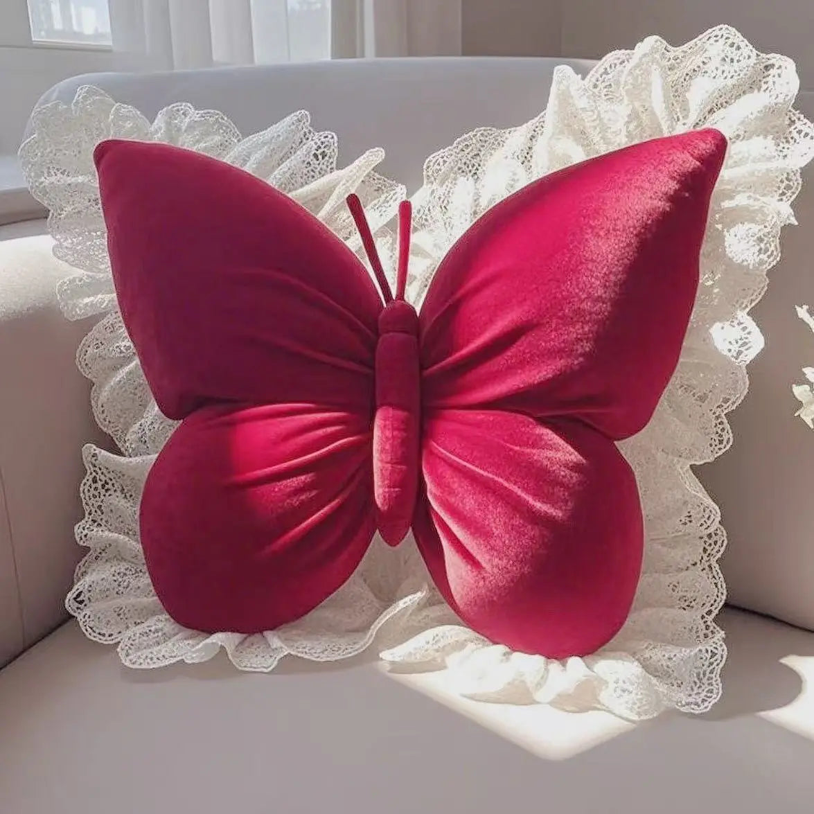 Ce coussin décoratif en forme de papillon rouge vif orné de dentelle blanche crée une impression chaleureuse et élégante sur ce meuble blanc.