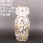 Vase en céramique orné de motifs floraux colorés et d'oiseaux dans un paysage naturel.