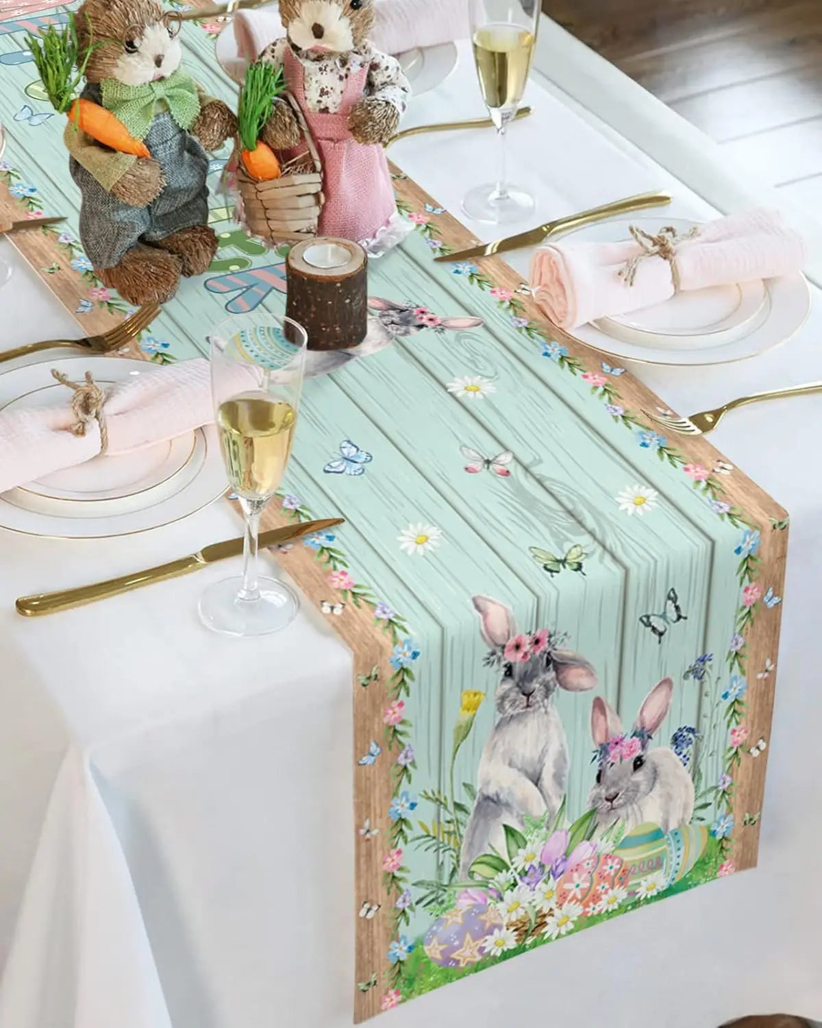 Table de fête printanière avec des nappes florales, des verres à champagne et des figurines de lapins en peluche.