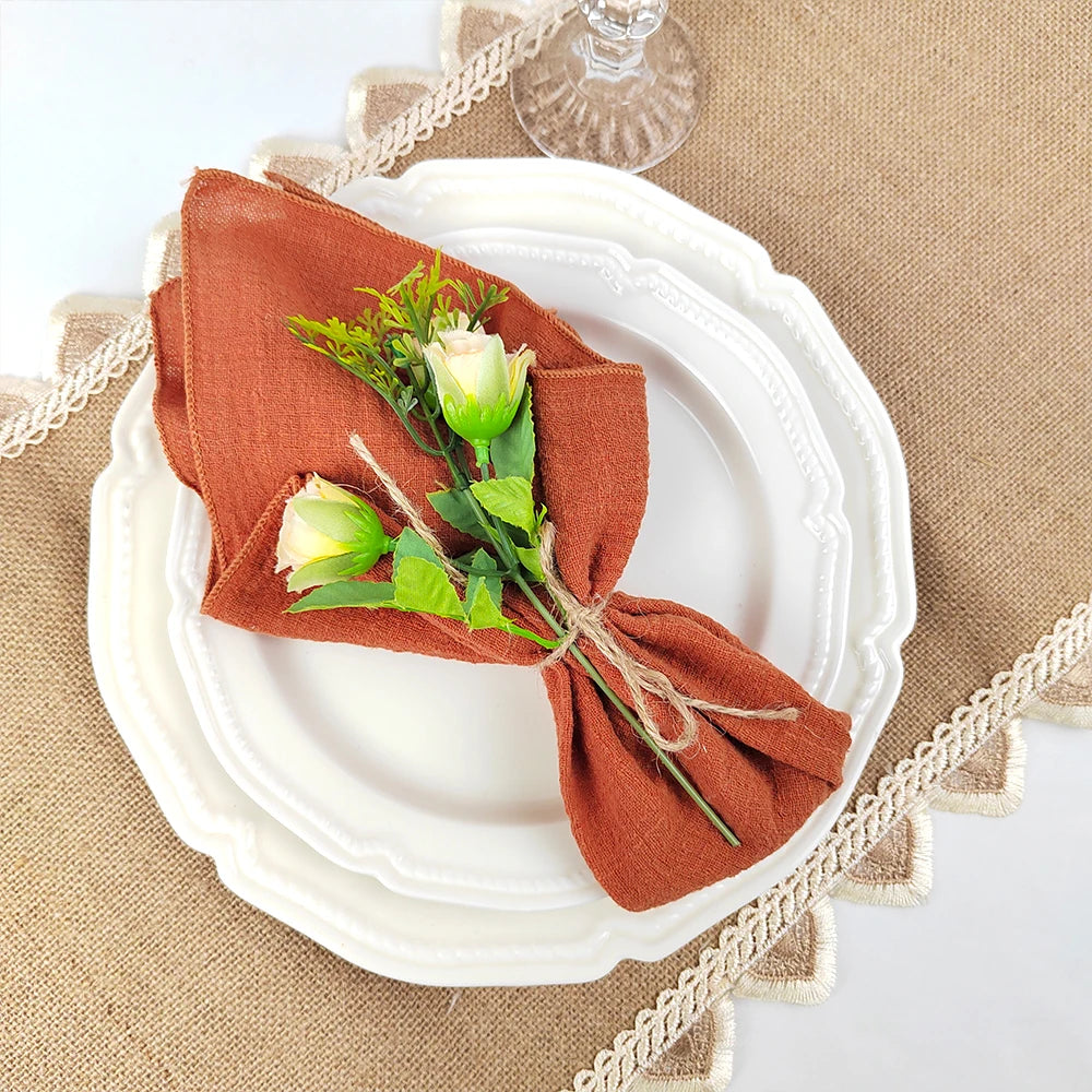 Une élégante décoration de table avec une serviette en tissu rouille et un bouquet de fleurs ornées.