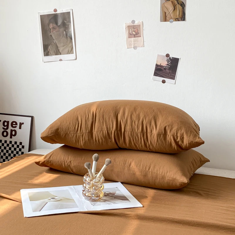 Un gros plan sur deux oreillers jaunes paille posés sur une surface texturée, entourés de photographies accrochées au mur et d'un objet décoratif posé sur un cadre.