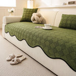 Un canapé confortable dans un intérieur cosy, avec un joli plaid et des coussins décoratifs en vert.