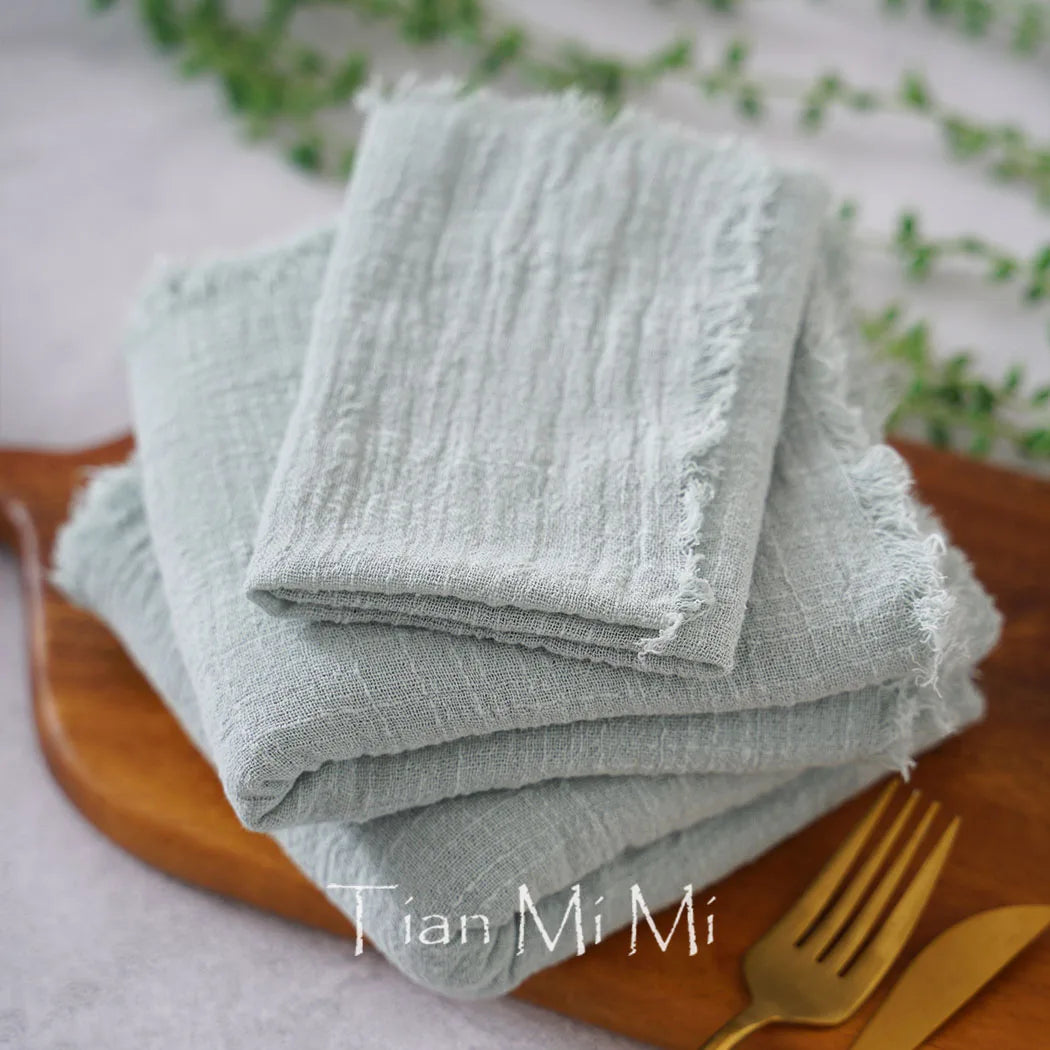 Serviettes de table en lin gris naturel, douces et texturées, posées sur un plateau en bois.
