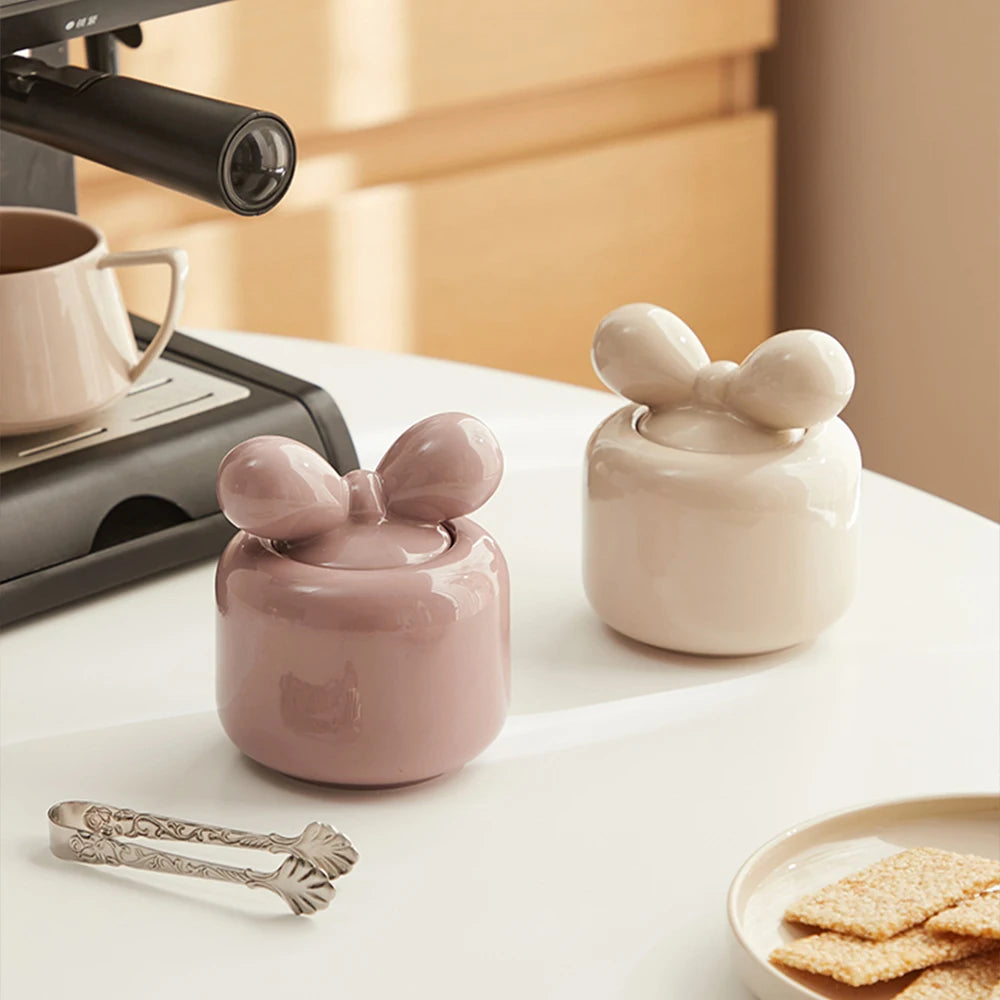 Des boîtes de rangement en céramique décorées de motifs floraux sur un comptoir de cuisine, à côté d'une tasse et de quelques biscuits.