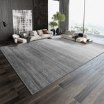 Pièce spacieuse et moderne avec un grand canapé et un tapis gris texturé, donnant sur une fenêtre avec vue sur l'extérieur.