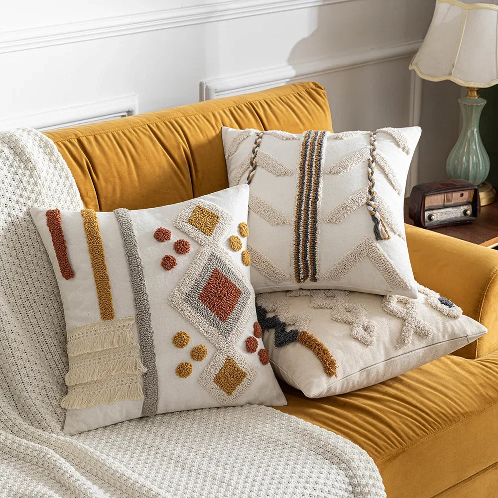 Un canapé jaune moutarde avec des coussins décoratifs ornés de motifs graphiques et texturés, créant une ambiance chaleureuse et cocooning.