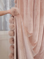 Zoom sur le rideau rose poudré en velours avec pompons moelleux cousus sur le bord, détail raffiné et chaleureux.